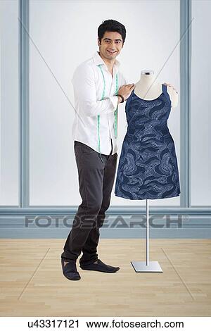 Male fashion designer standing by mannequin View Large Photo Image Stock Image - Male fashion designer standing by mannequin . Fotosearch