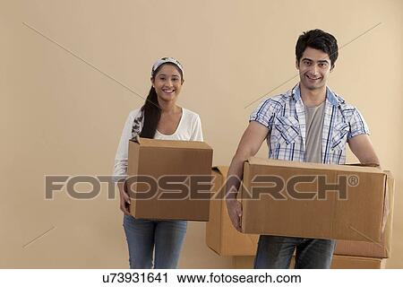 Man and woman carrying cardboard boxes while moving in new house View Large Photo Image Stock Image - Man and woman carrying cardboard boxes while moving in new house . Fotosearch