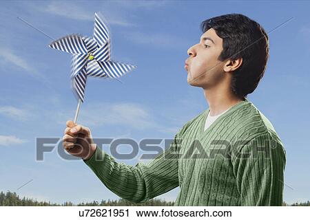 Stock Image - Man blowing on a pinwheel . Fotosearch