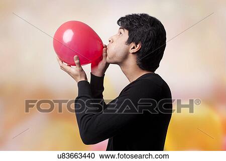 Stock Image - Man blowing up a balloon . Fotosearch