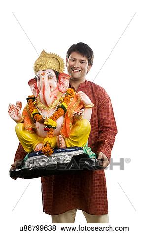 Stock Photo - Man carrying a Ganesh idol . Fotosearch