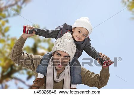 Stock Photograph - Man giving boy piggy back ride outdoors . Fotosearch