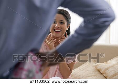 Man hiding gift behind his back from woman View Large Photo Image Stock Image - Man hiding gift behind his back from woman . Fotosearch