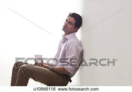 Man holding a mug of tea leaning against wall View Large Photo Image Stock Photo - Man holding a mug of tea leaning against wall. Fotosearch