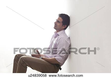 Man holding a mug of tea leaning against wall View Large Photo Image Stock Photo - Man holding a mug of tea leaning against wall. Fotosearch