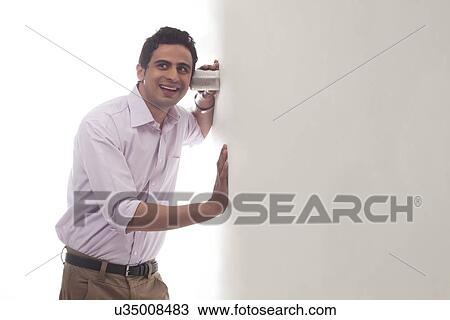 Man holding glass against wall listening View Large Photo Image Stock Image - Man holding glass against wall listening. Fotosearch