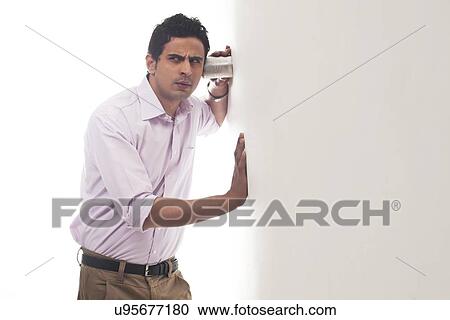 Man holding glass against wall listening View Large Photo Image Stock Image - Man holding glass against wall listening. Fotosearch
