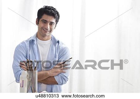 Stock Image - Man holding paintbrush in art studio . Fotosearch