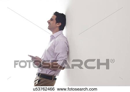 Stock Photograph - Man leaning against a wall smiling. Fotosearch