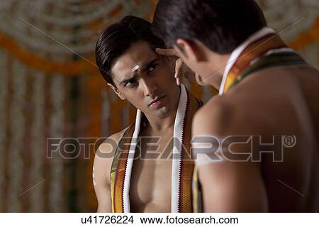 Picture - Man looking at himself in mirror . Fotosearch