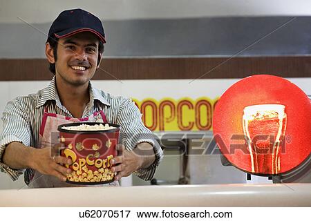 Man offering popcorn at a counter View Large Photo Image Stock Photo - Man offering popcorn at a counter . Fotosearch