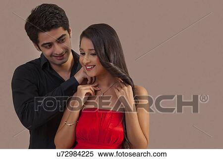 Stock Photography - Man placing necklace on woman's neck . Fotosearch