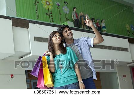 Stock Image - Man pointing at something in shopping mall . Fotosearch