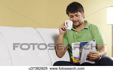 Man reading a magazine while drinking coffee View Large Photo Image Stock Photo - Man reading a magazine while drinking coffee . Fotosearch