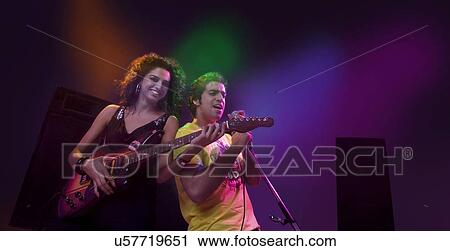 Man singing while a woman plays the guitar View Large Photo Image Stock Image - Man singing while a woman plays the guitar . Fotosearch
