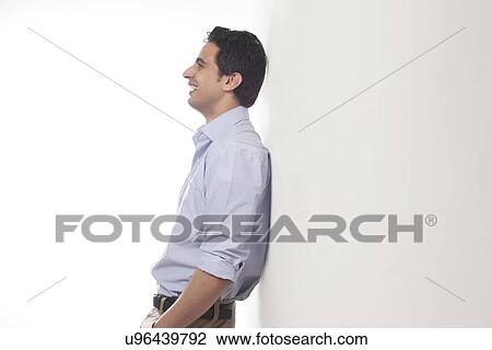 Man standing against a wall smiling View Large Photo Image Stock Image - Man standing against a wall smiling. Fotosearch