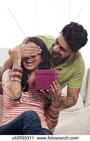 Man surprising a woman with a gift View Large Photo Image Stock Image - Man surprising a woman with a gift. Fotosearch