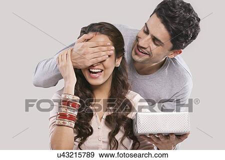 Man surprising a woman with a gift View Large Photo Image Stock Photo - Man surprising a woman with a gift. Fotosearch