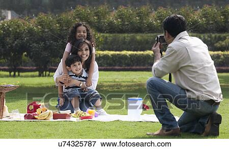 Stock Photo - Man taking a photograph of his family . Fotosearch