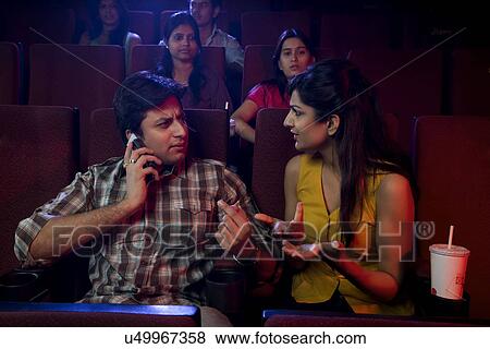 Man talking on a mobile phone in a cinema hall View Large Photo Image Stock Photo - Man talking on a mobile phone in a cinema hall . Fotosearch