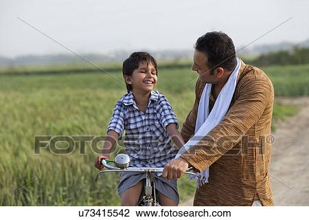 Man teaching son to ride bicycle View Large Photo Image Stock Image - Man teaching son to ride bicycle . Fotosearch