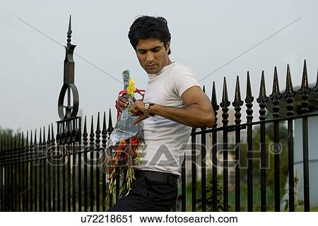 Man with a bouquet of flowers looking at his watch View Large Photo Image Stock Image - Man with a bouquet of flowers looking at his watch . Fotosearch