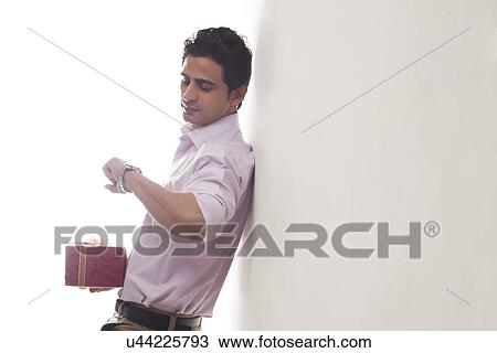 Stock Image - Man with a gift checking time. Fotosearch