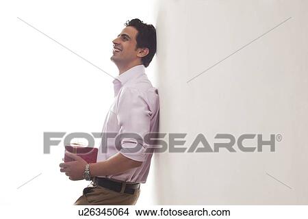 Picture - Man with a gift leaning against wall. Fotosearch