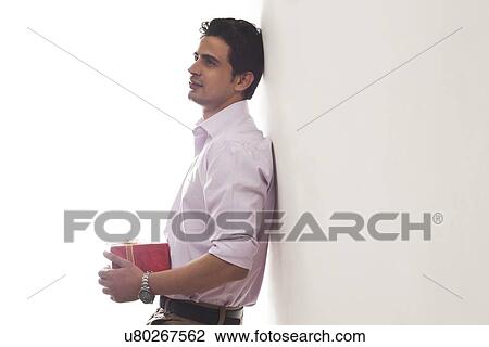 Stock Image - Man with a gift leaning against wall. Fotosearch