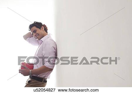 Man with a gift leaning against wall View Large Photo Image Stock Photo - Man with a gift leaning against wall. Fotosearch