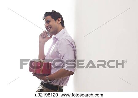 Man with a gift talking on a mobile phone View Large Photo Image Stock Image - Man with a gift talking on a mobile phone. Fotosearch