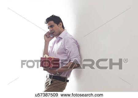 Stock Photo - Man with a gift talking on a mobile phone. Fotosearch