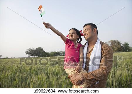 Man with his daughter holding Indian flag in an agricultural field View Large Photo Image Picture - Man with his daughter holding Indian flag in an agricultural field . Fotosearch
