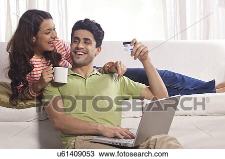 Stock Image - Married couple with credit card and laptop. Fotosearch