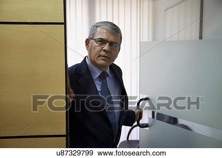 Mature businessman walking out of office cabin View Large Photo Image Stock Photo - Mature businessman walking out of office cabin . Fotosearch