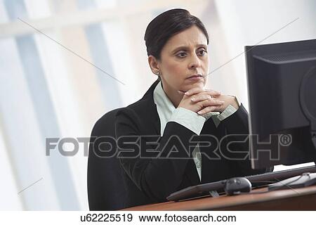 Stock Photo - Mature businesswoman looking at computer with concentration . Fotosearch