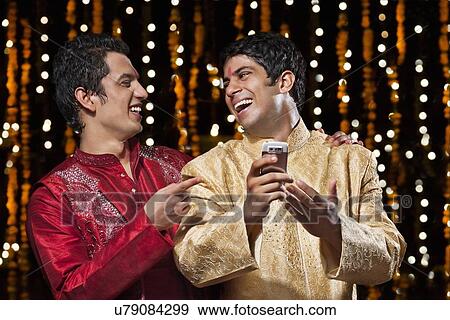 Stock Photo - Men laughing at sms on mobile phone. Fotosearch