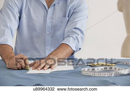 Stock Image - Mid section of male fashion designer working in fashion studio . Fotosearch