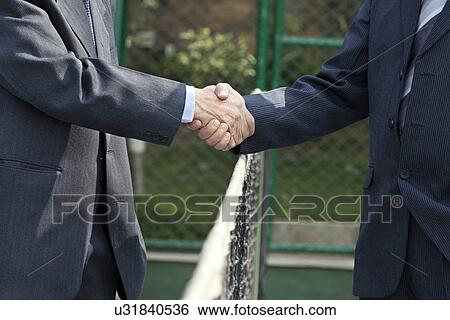 Midsection of professionals shaking hands over tennis net in court View Large Photo Image Stock Photograph - Midsection of professionals shaking hands over tennis net in court . Fotosearch