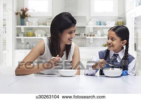 Picture - Mother and daughter at table eating breakfast . Fotosearch