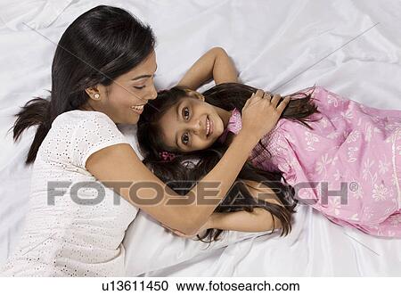 Mother and daughter lying together in bed View Large Photo Image Stock Image - Mother and daughter lying together in bed . Fotosearch