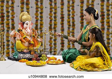 Mother and daughter performing a pooja View Large Photo Image Stock Photo - Mother and daughter performing a pooja . Fotosearch