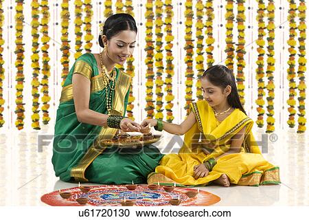 Mother and daughter placing diyas on a rangoli View Large Photo Image Stock Image - Mother and daughter placing diyas on a rangoli . Fotosearch
