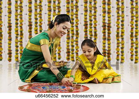 Mother and daughter placing diyas on a rangoli  View Large Photo Image Stock Image - Mother and daughter placing diyas on a rangoli . Fotosearch
