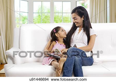 Mother and daughter sitting together with a story book View Large Photo Image Picture - Mother and daughter sitting together with a story book . Fotosearch