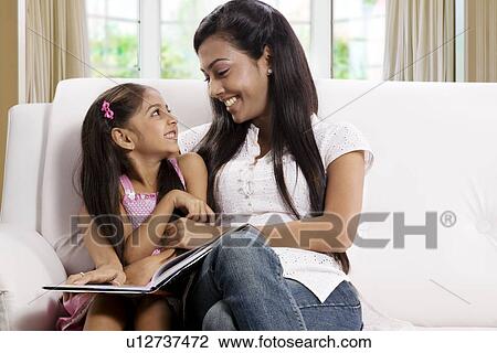 Mother and daughter sitting together with a book View Large Photo Image Stock Image - Mother and daughter sitting together with a book . Fotosearch