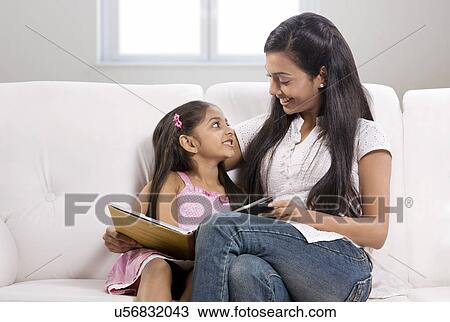 Stock Image - Mother and daughter sitting together with a story book . Fotosearch