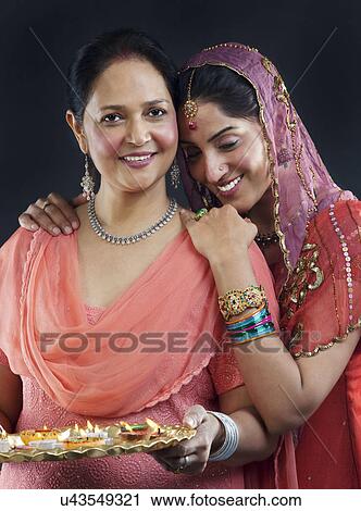 Stock Image - Mother and daughter with a tray of diyas . Fotosearch