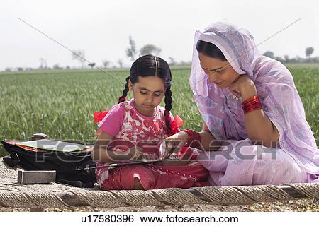 Mother assisting daughter with her homework View Large Photo Image Stock Photograph - Mother assisting daughter with her homework . Fotosearch