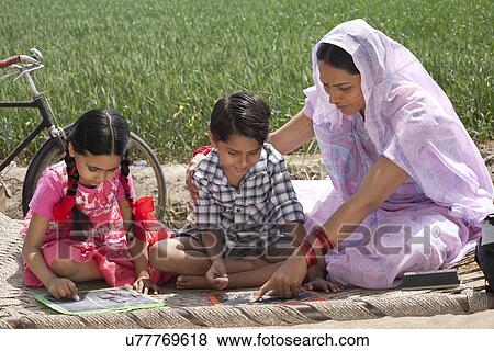 Stock Photo - Mother helping daughter and son with their homework . Fotosearch